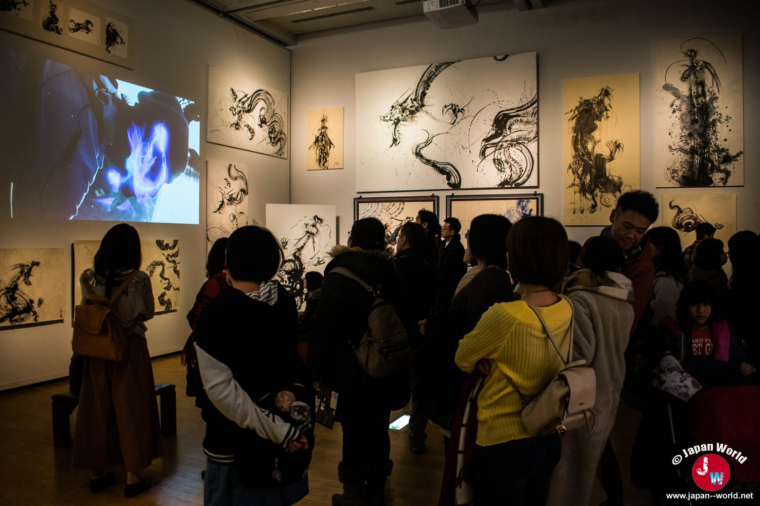 Visiteurs regardant une vidéo au milieu des œuvres à l'encre de Yuki Nishimoto