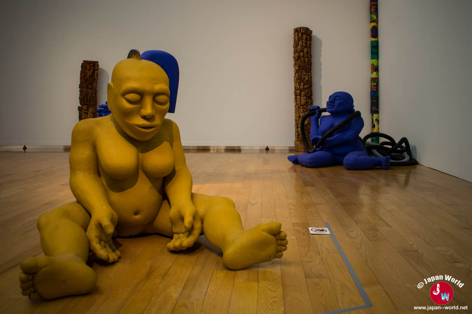 Grande sculpture jaune assise devant une sculpture bleue dans l'exposition permanente