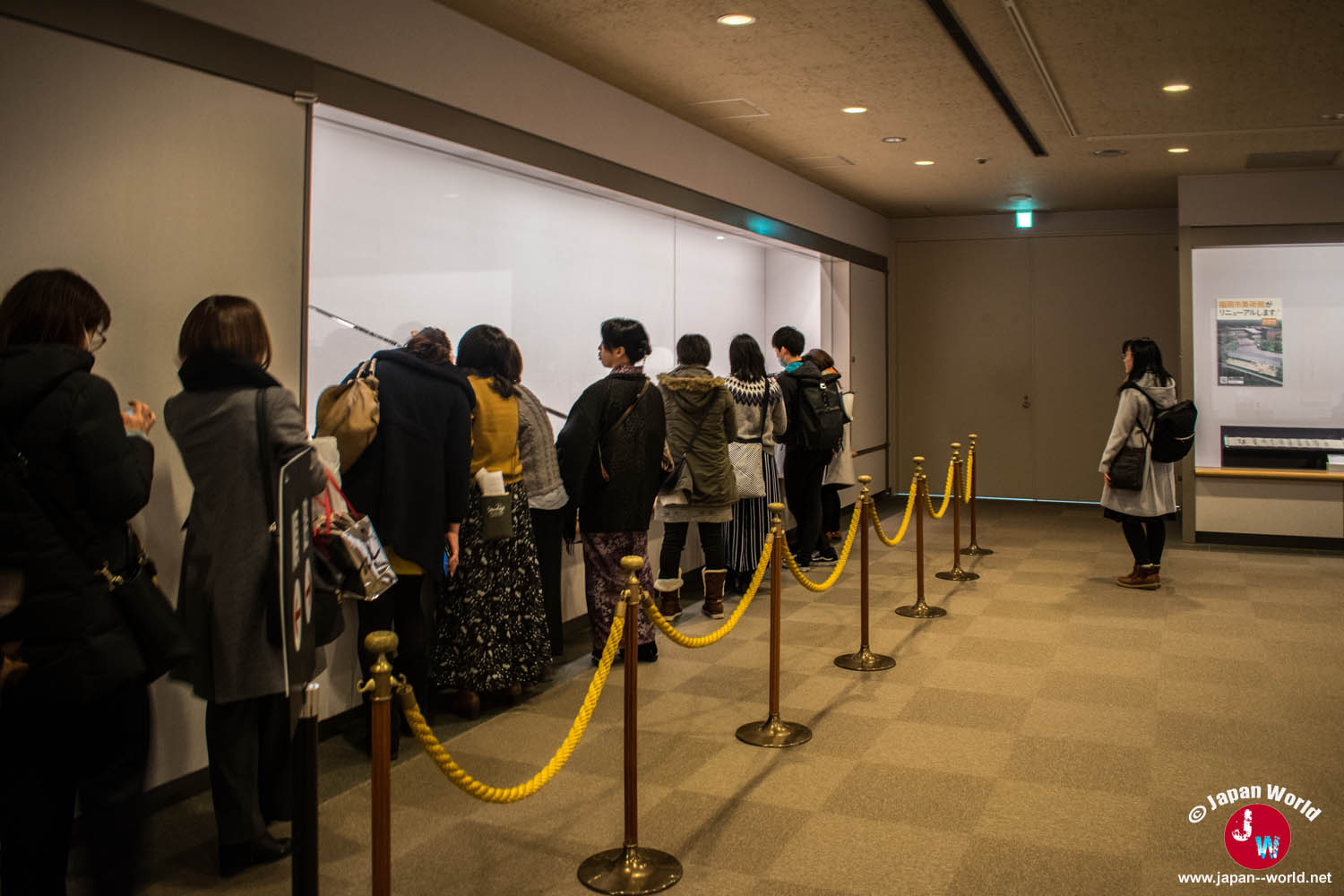 File de visiteurs devant les armes exposées dans la première exposition mise en vedette