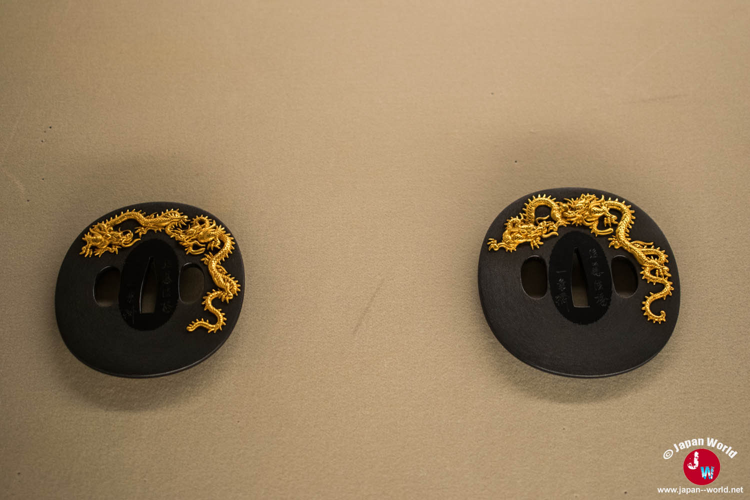 Deux tsuba rondes noires ornées de dragons dorés