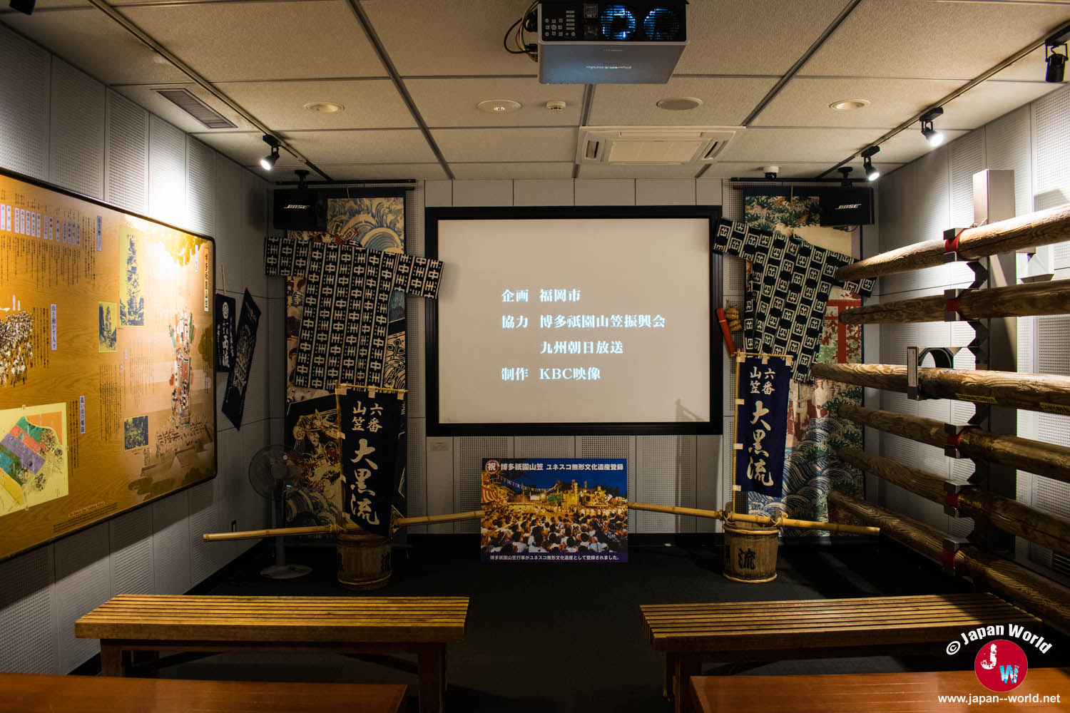 Salle de projection consacrée au festival Hakata Gion Yamakasa avec écran et bancs