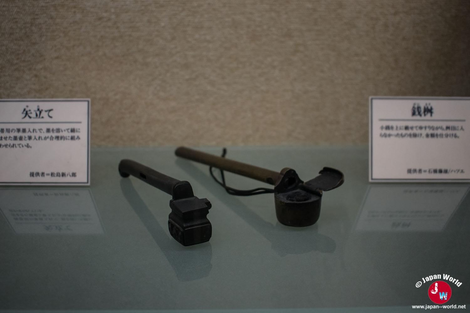 Nécessaire d'écriture portatif et pipe japonaise exposés sous vitrine