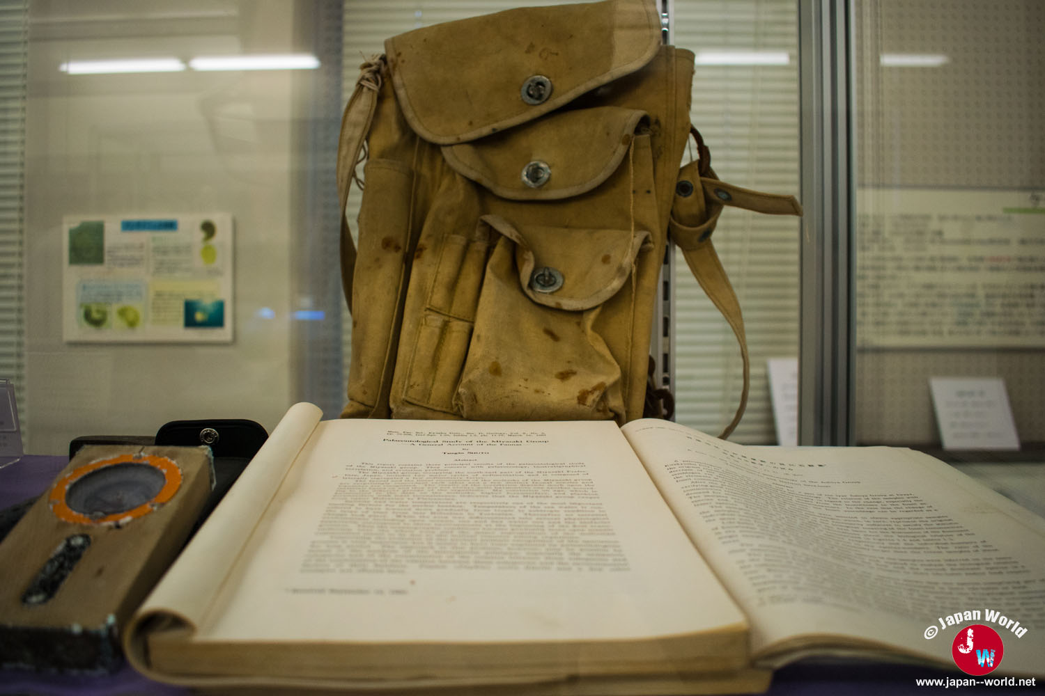 Sac de terrain et carnet de recherche ouverts dans une vitrine du musée
