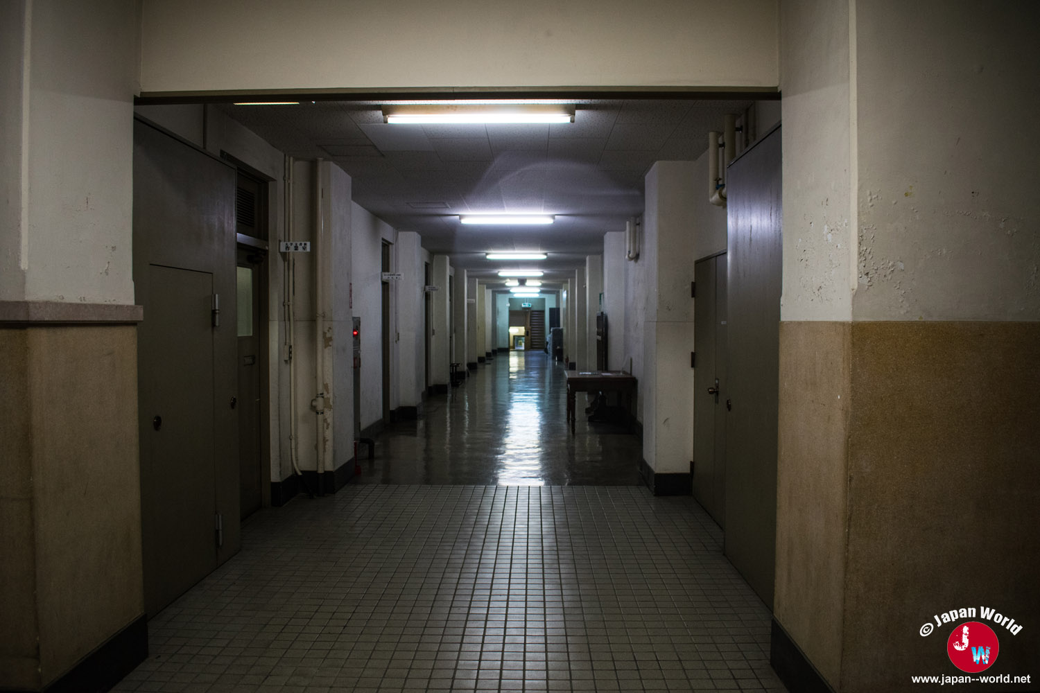 Long couloir aux murs clairs et au sol carrelé dans le bâtiment de l'université de Kyushu