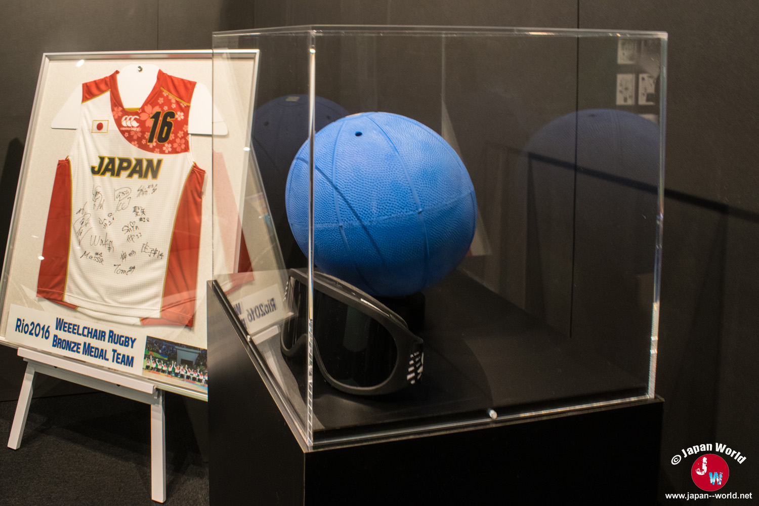 Ballon de goalball et maillot dédicacé de l'équipe japonaise de rugby fauteuil exposés sous vitrine