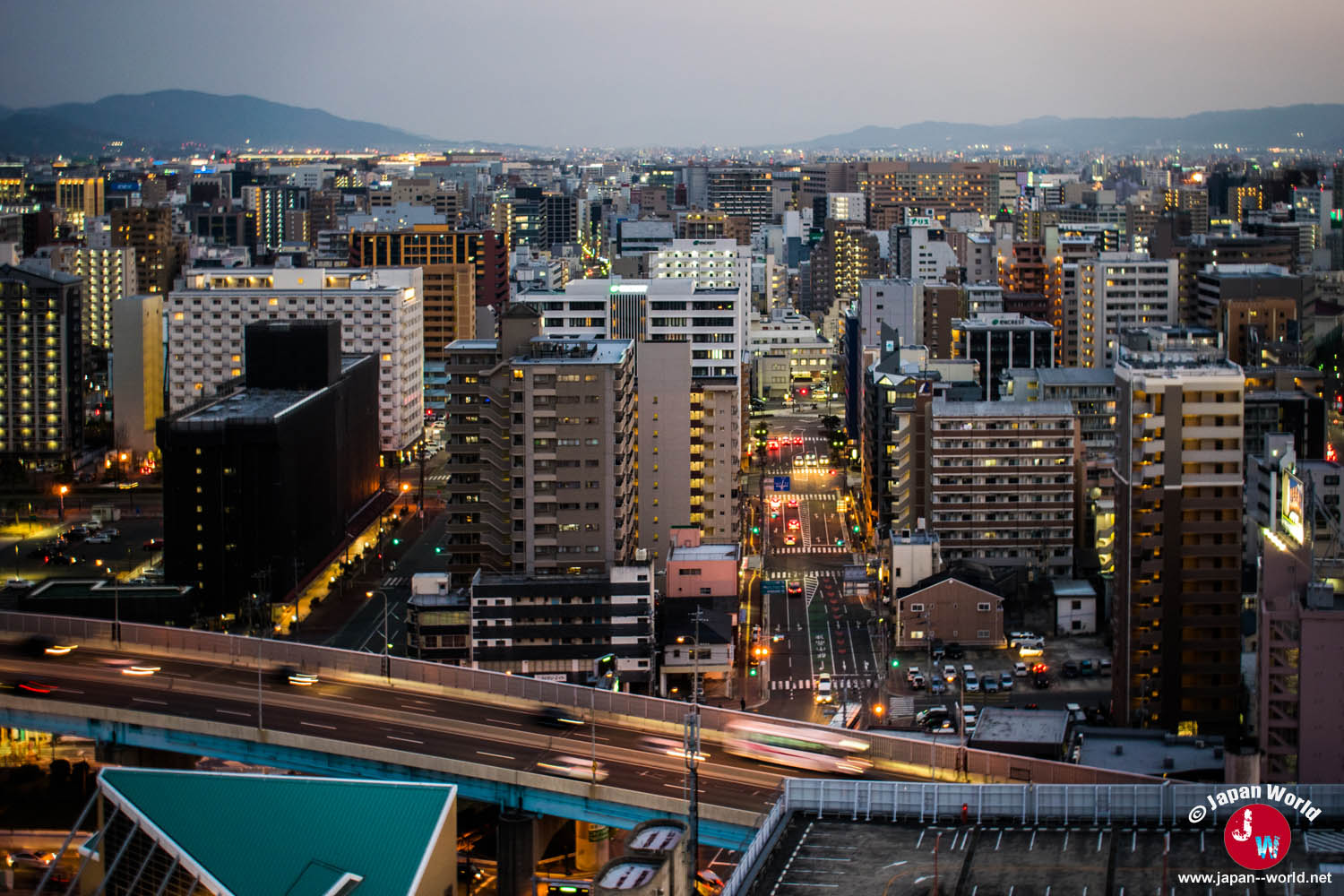 Avenue et immeubles du centre de Fukuoka éclairés à la tombée de la nuit
