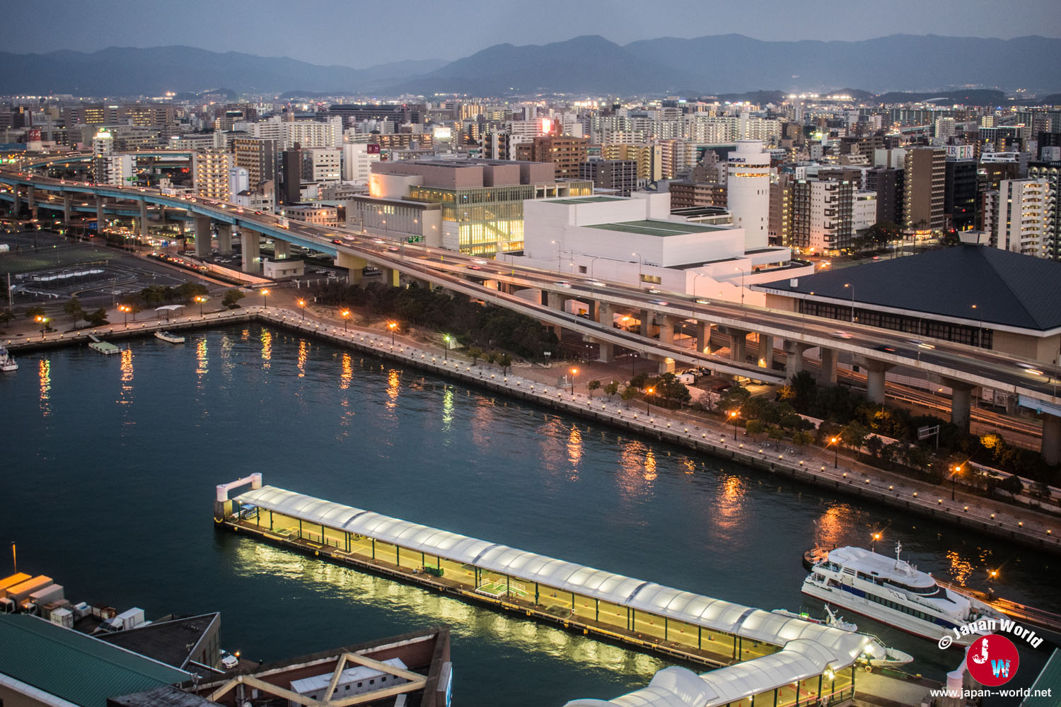Terminal maritime et front urbain de Fukuoka se reflétant dans l'eau au crépuscule