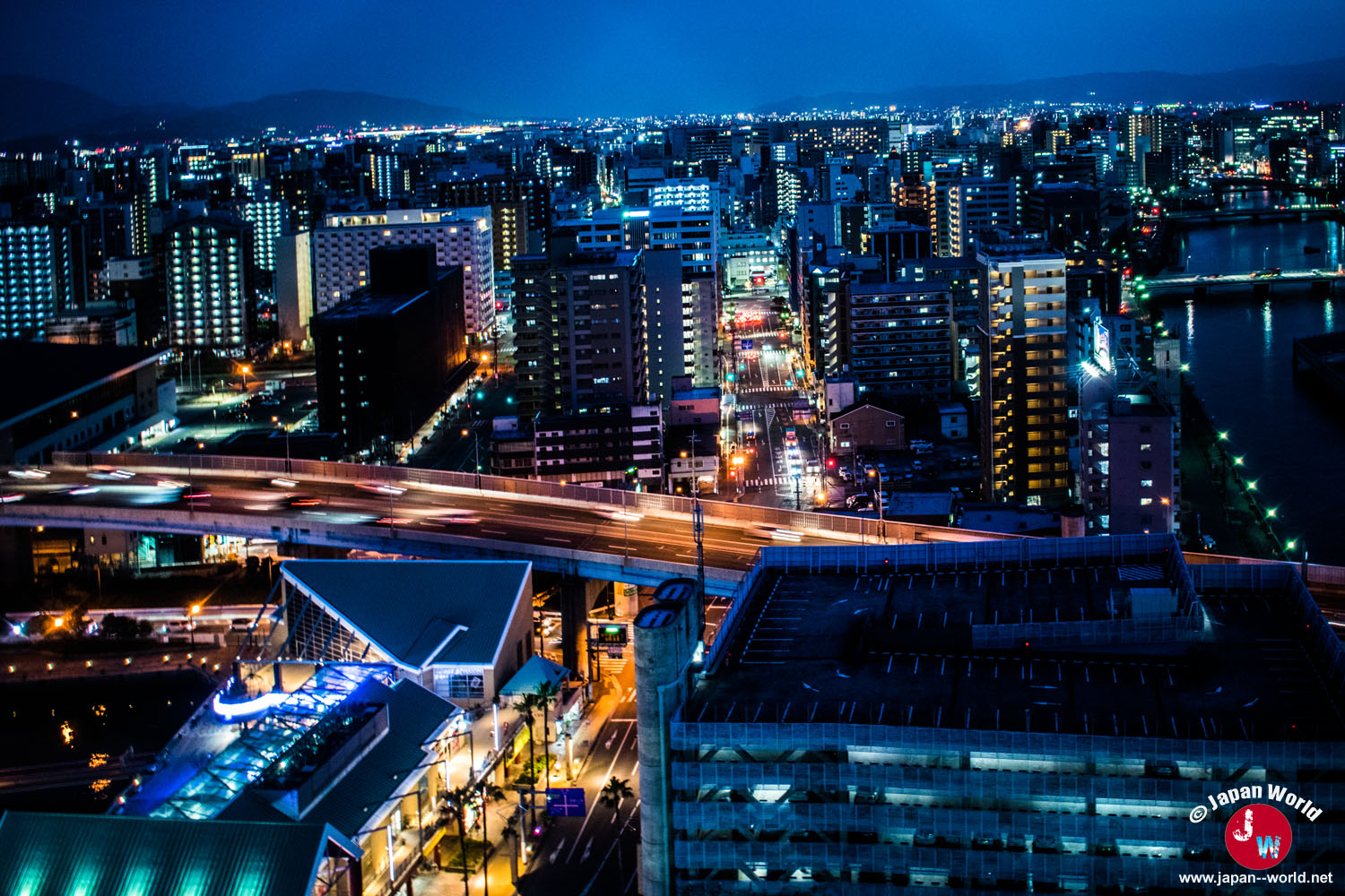 Centre-ville de Fukuoka illuminé de nuit avec la voie rapide au premier plan