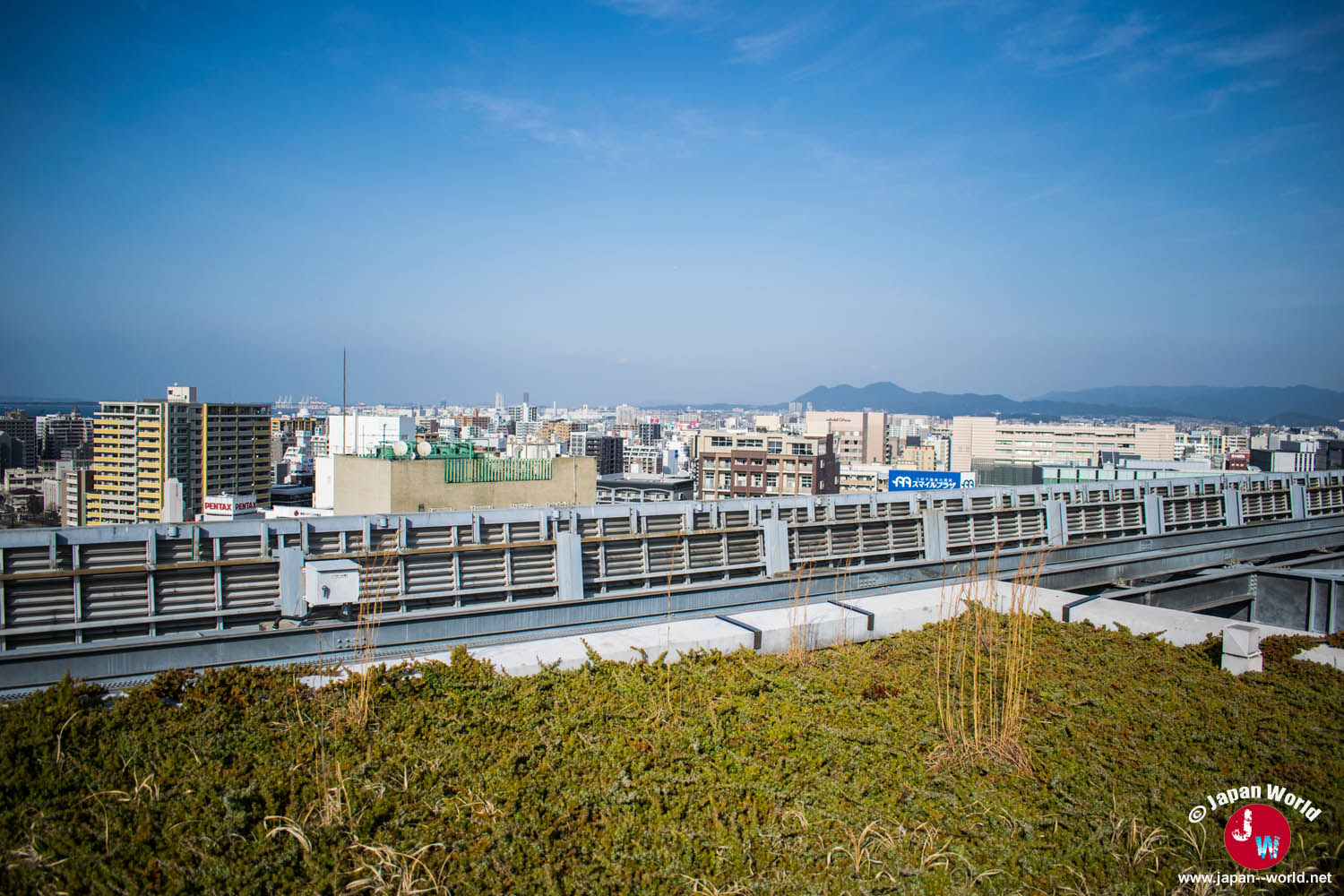 Toits de Fukuoka et montagnes derrière la végétation d'ACROS