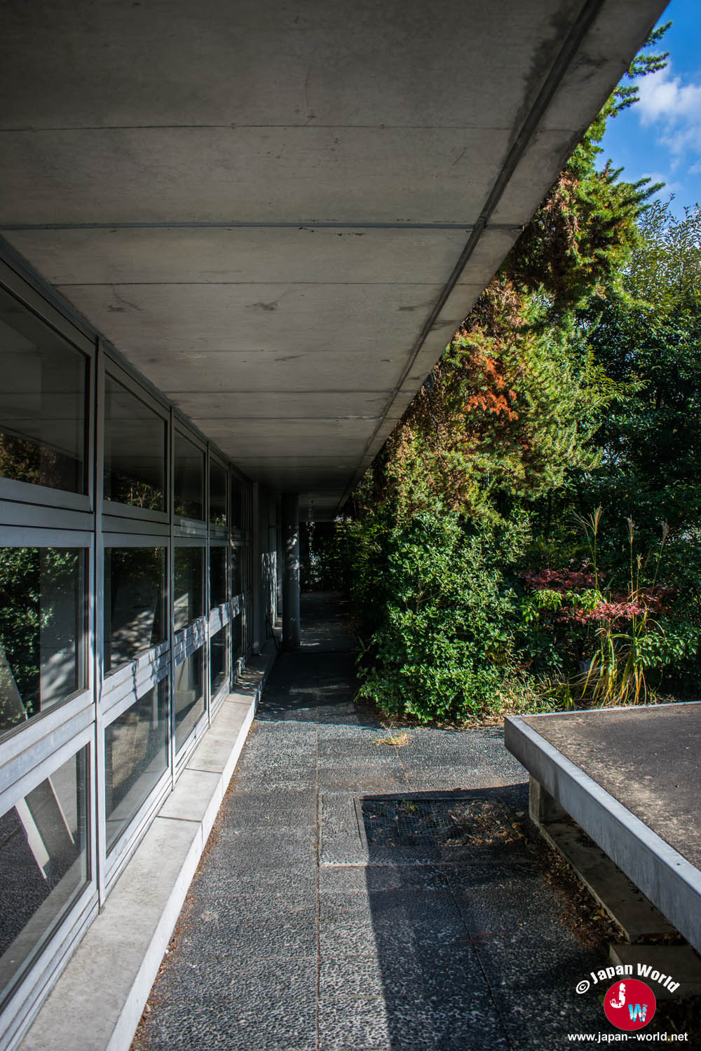 Passage couvert entre la façade vitrée et la végétation d'ACROS Fukuoka