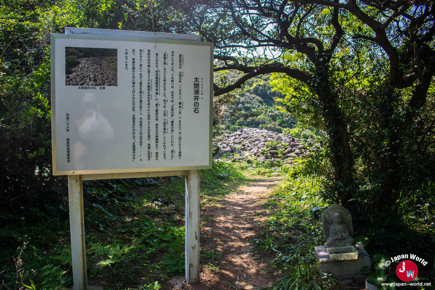 Panneau explicatif devant un monticule de pierres à Ainoshima