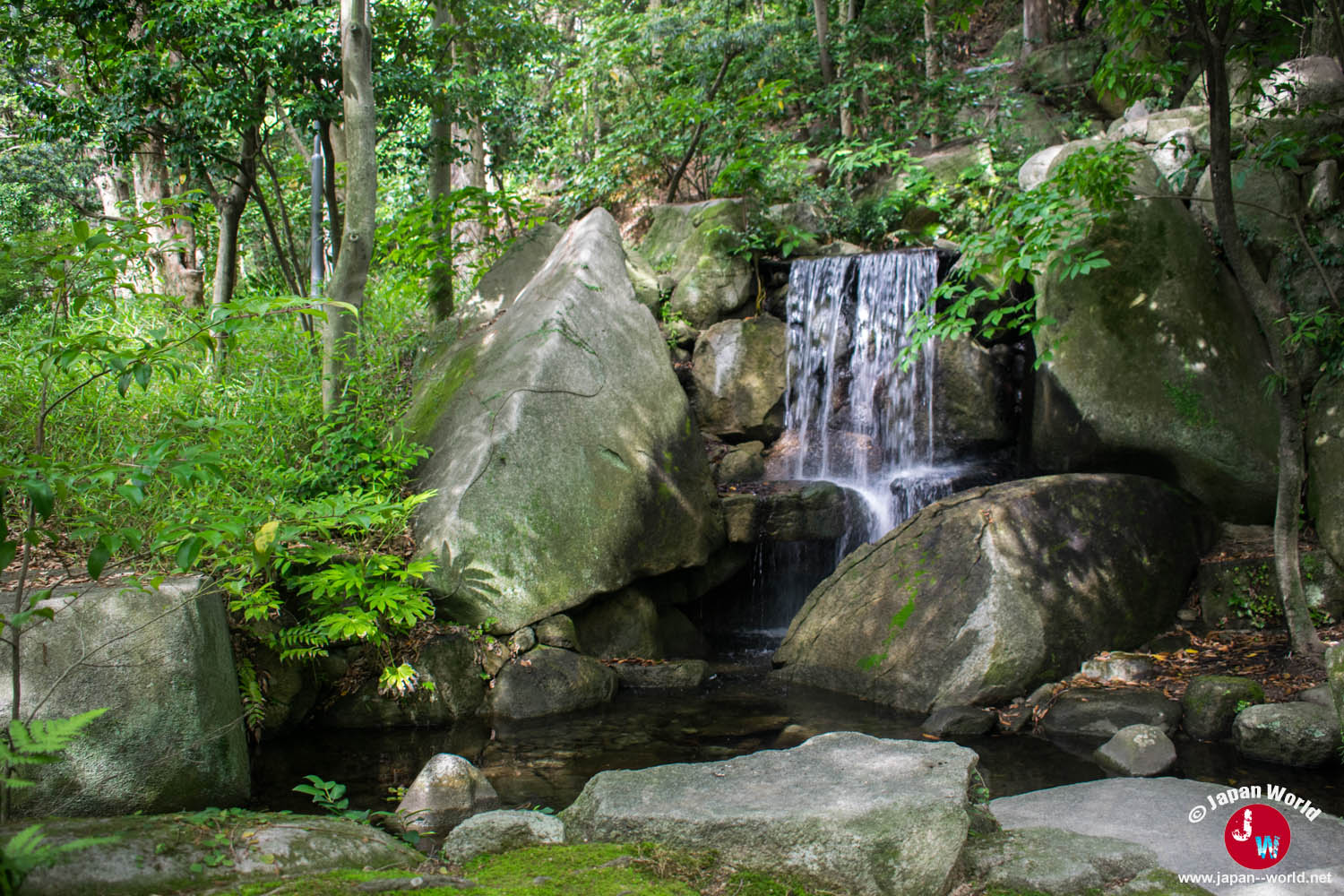 Petite cascade entourée de rochers au parc Yusentei