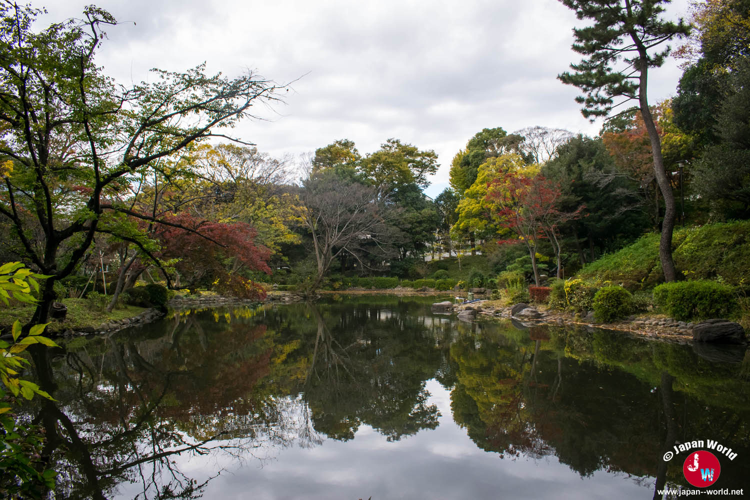 Étang bordé d'arbres aux couleurs d'automne dans le parc mémorial d'Arisugawa-no-miya