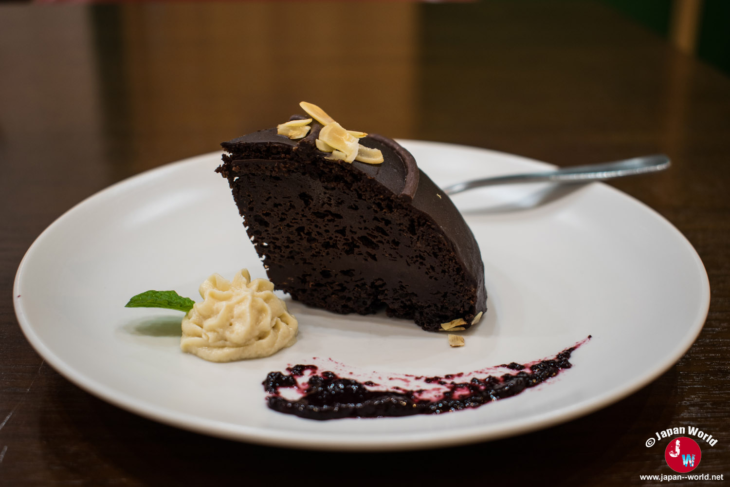 Part de gâteau au chocolat accompagnée de crème et d'un coulis de fruits rouges au RotaCafe