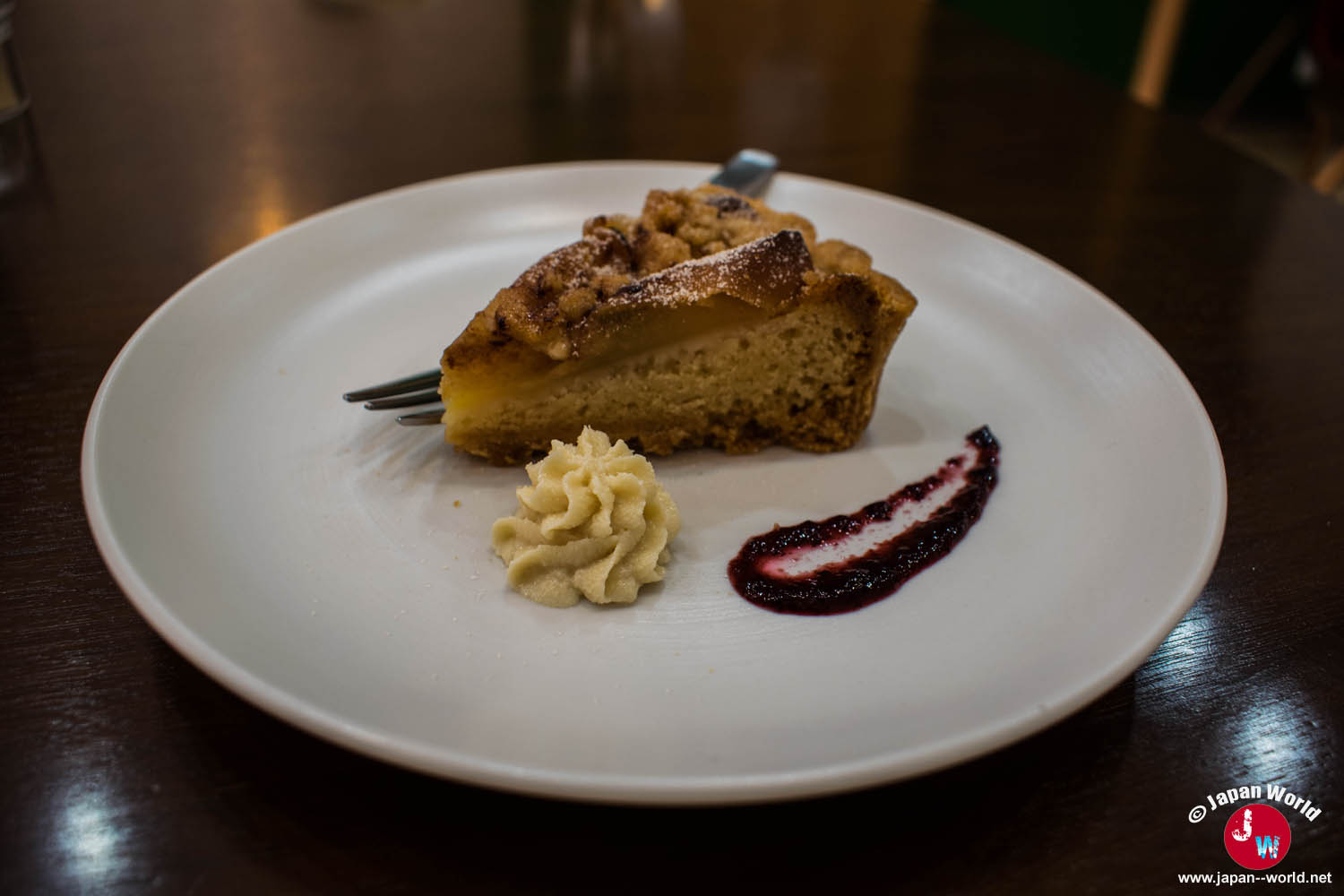 Part de tarte aux fruits servie avec de la crème et un coulis de fruits rouges au RotaCafe