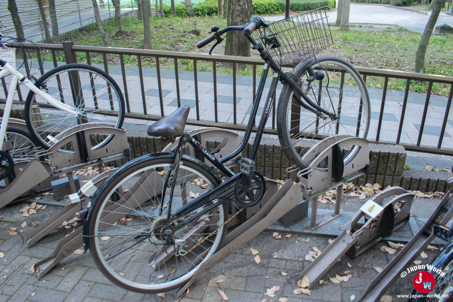 Mamachari noir avec panier avant stationné dans un parking à vélos au Japon