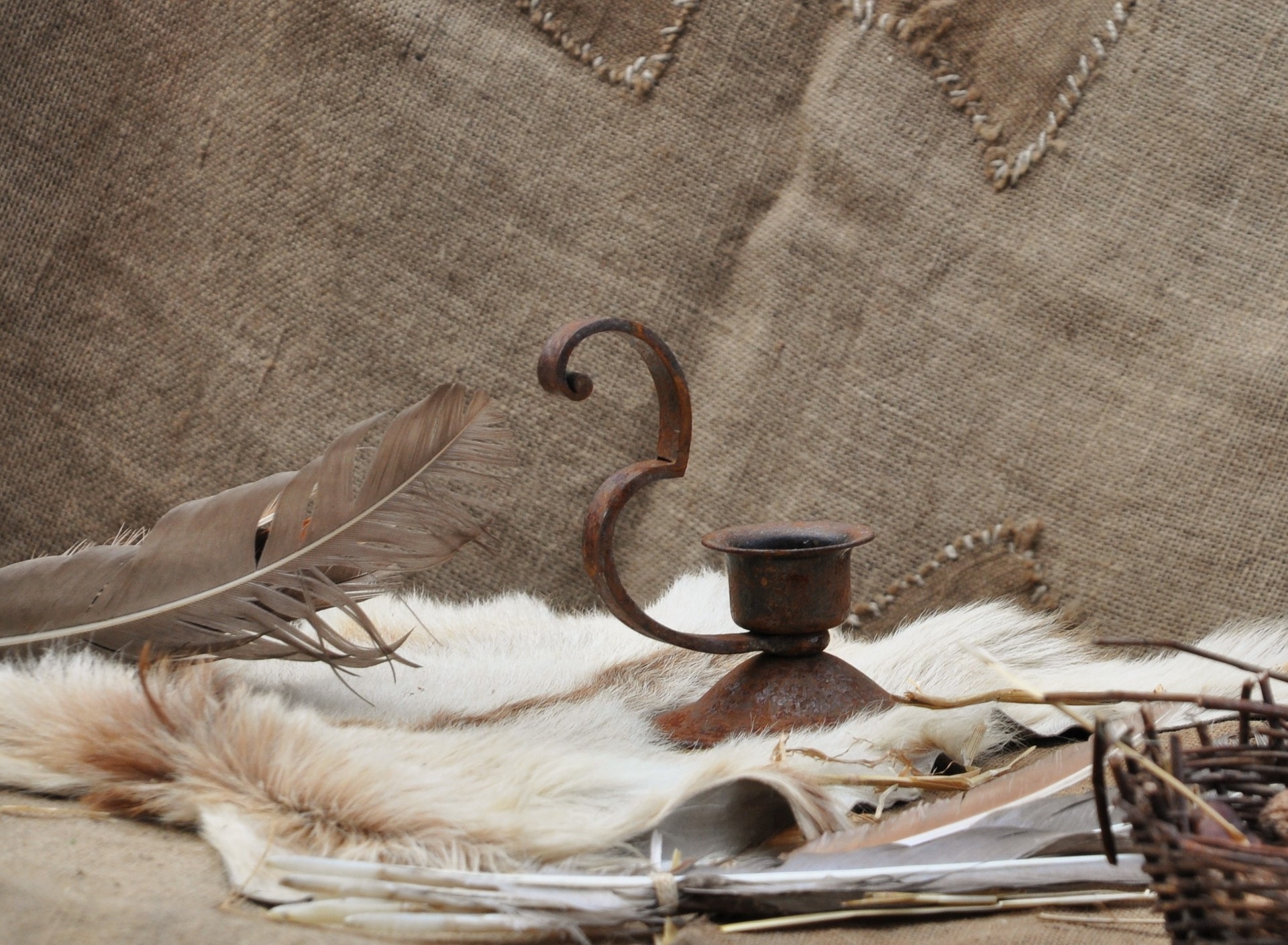 Plume et bougeoir en métal disposés sur des étoffes anciennes