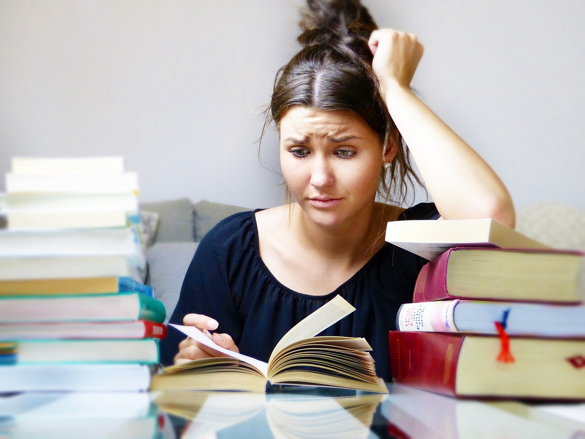 Étudiante perplexe entourée de livres ouverts et empilés