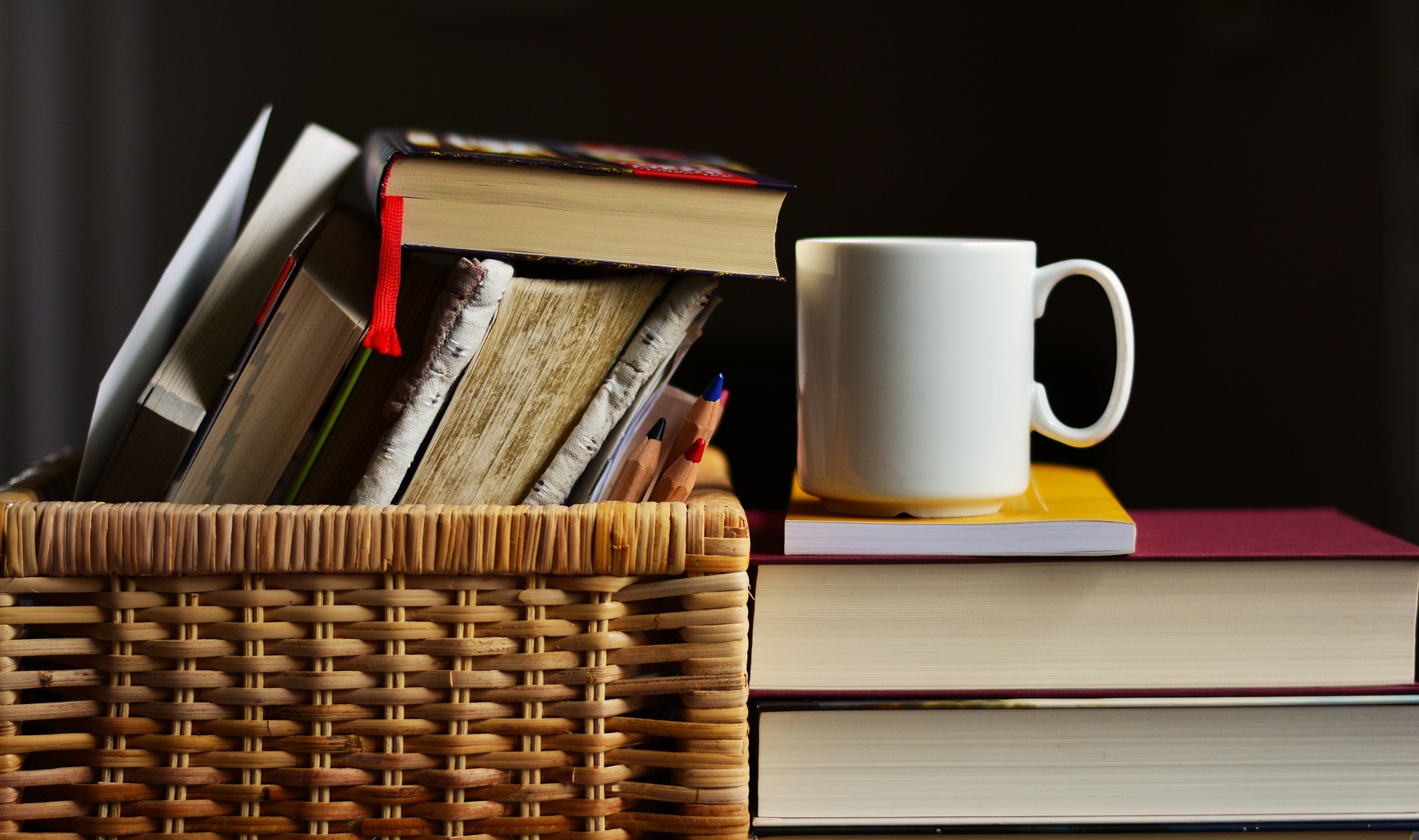 Livres et crayons rangés dans un panier à côté d’une tasse blanche