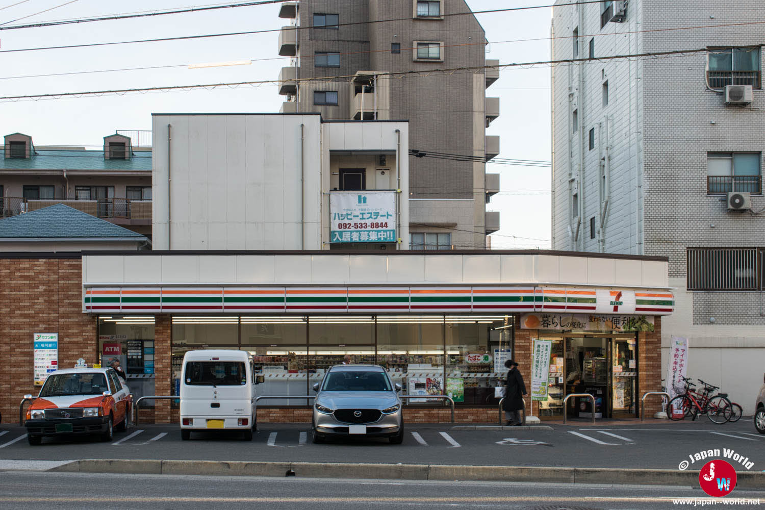 Façade d’un 7-Eleven avec parking devant des immeubles résidentiels