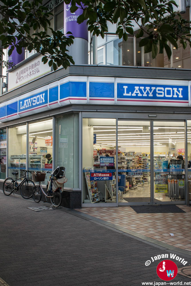 Entrée d’un magasin Lawson en angle de rue avec des vélos stationnés