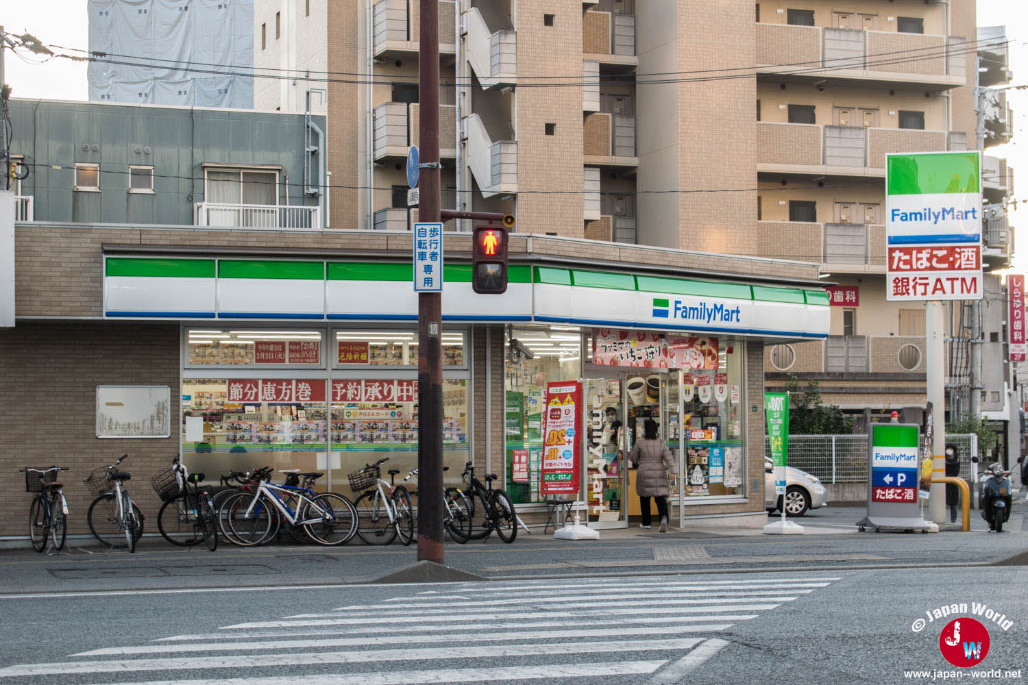 Façade d’un FamilyMart à un carrefour avec des vélos garés devant le magasin
