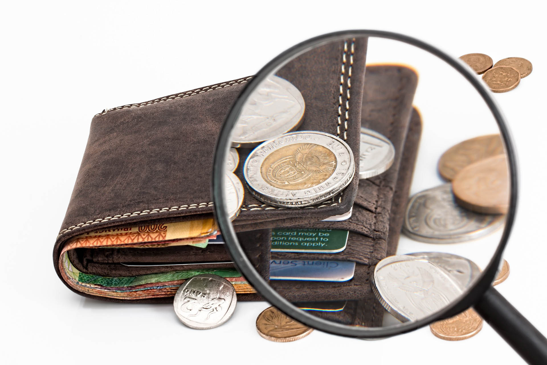 Portefeuille et pièces de monnaie sous une loupe