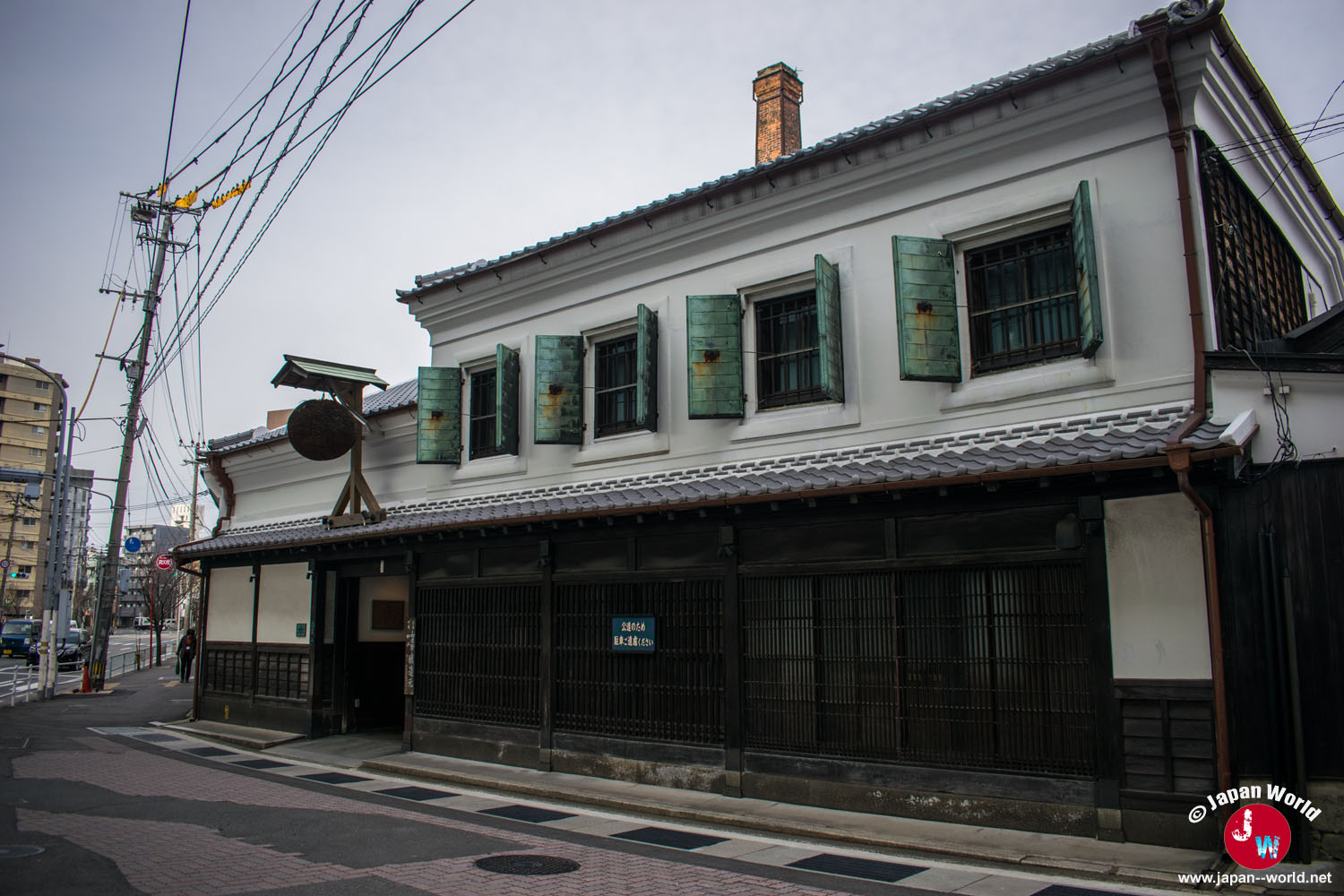 Façade de la brasserie Ishikura avec ses murs blancs, ses panneaux en bois sombre et sa cheminée en briques