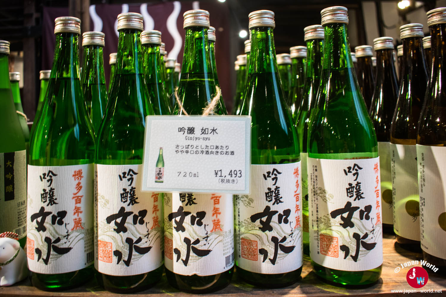 Rangées de bouteilles vertes de saké ginjo alignées dans la boutique de la brasserie Ishikura