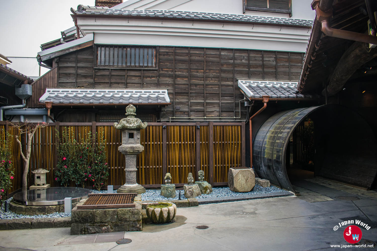 Cour intérieure de la brasserie Ishikura avec une lanterne en pierre, des façades en bois et un passage circulaire
