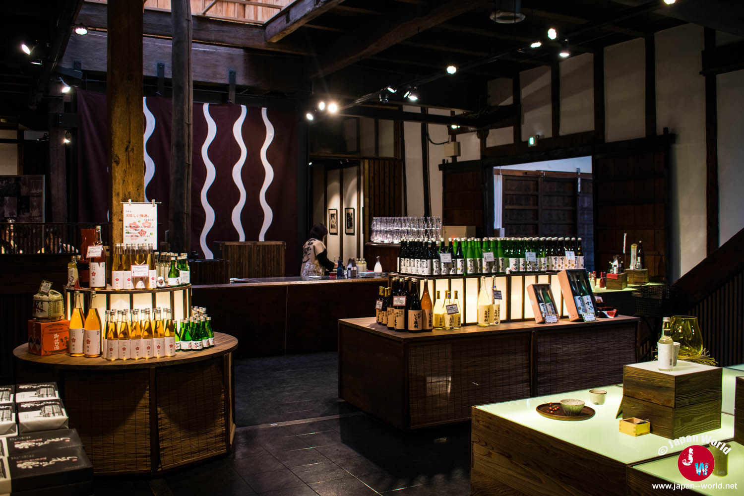 Intérieur de la boutique Ishikura avec des bouteilles de saké disposées sur plusieurs présentoirs